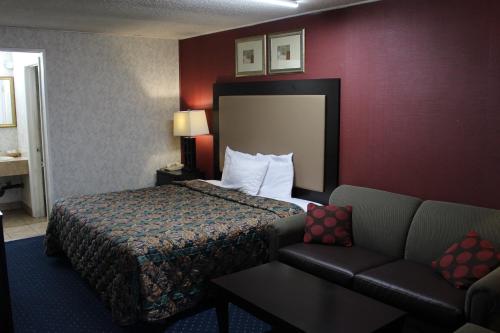 a hotel room with a bed and a couch at Budgetel Inn & Suites Atlantic City in Galloway
