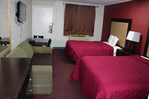two beds in a hotel room with red walls at Budgetel Inn & Suites Atlantic City in Galloway