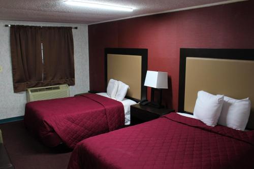 a hotel room with two beds and red walls at Budgetel Inn & Suites Atlantic City in Galloway