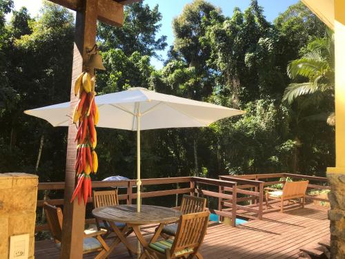 a table and chairs with an umbrella on a deck at Pousada Casa da Montanha in Angra dos Reis
