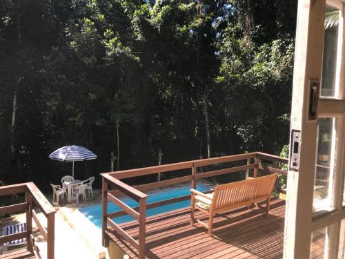 a deck with a bench and an umbrella next to a pool at Pousada Casa da Montanha in Angra dos Reis