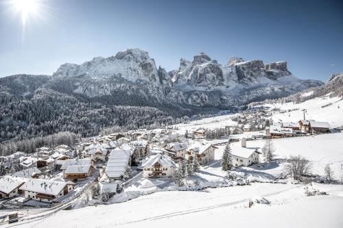a village covered in snow with mountains in the background at Hotel Jägerhof in Colfosco