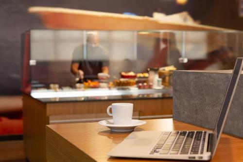 a laptop computer sitting on a table with a cup of coffee at ibis Sao Jose dos Campos Dutra in São José dos Campos