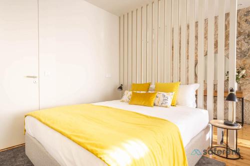 - une chambre dotée d'un grand lit avec des draps jaunes dans l'établissement Light-filled Bonjardim Apartments, à Porto