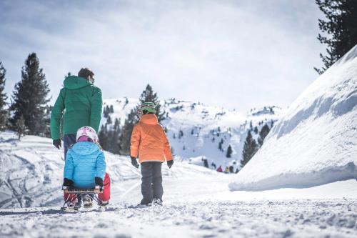 a man and two children walking in the snow at Hotel Jägerhof in Colfosco