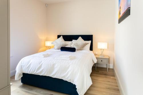ein Schlafzimmer mit einem Bett mit weißer Bettwäsche und zwei Lampen in der Unterkunft Hilltown Lodges No4 in Hilltown