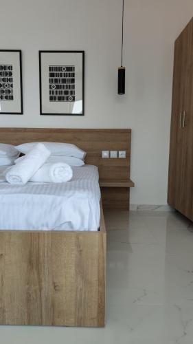 a bedroom with a wooden bed with white sheets and pillows at Finikas Suites & Apartments Airport By Airstay in Artemida