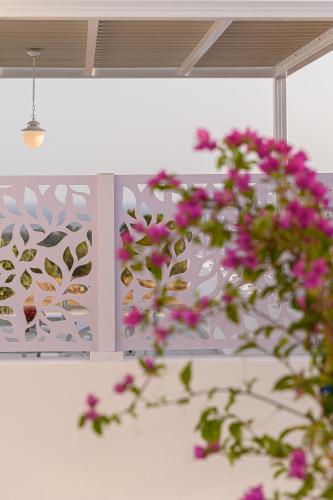 a plant with pink flowers in front of a wall at Dionisos Suites in Lixouri