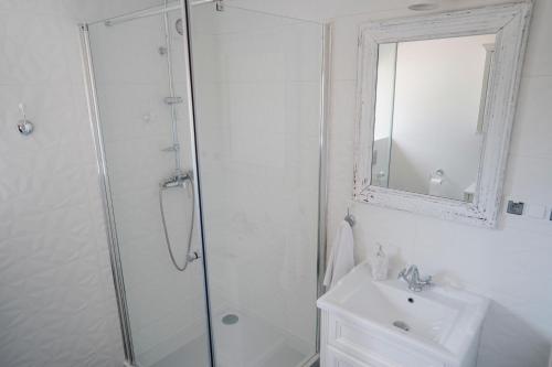 La salle de bains blanche est pourvue d'une douche et d'un lavabo. dans l'établissement Tatarska Zagroda - Agroturystyka Dolina Baryczy Noclegi - Domek Danielek, à Krośnice