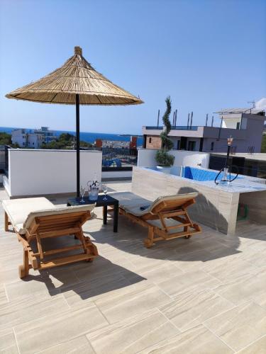 un patio avec deux chaises et un parasol sur le toit dans l'établissement Villa Primo Opus, à Ksamil