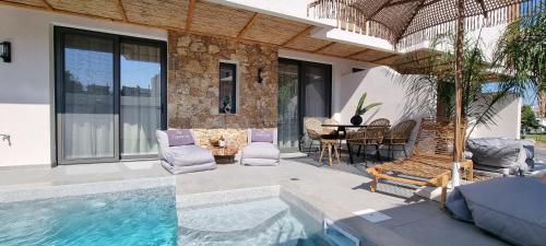 um pátio com uma piscina, cadeiras e uma mesa em Olvion Luxury Living em Kallithea Halkidikis