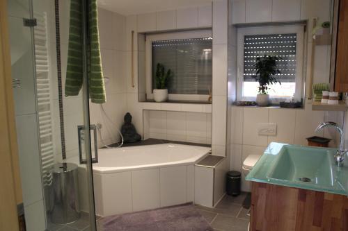 a bathroom with a tub and a sink at Ferienwohnung Forellenhof in Oberschwarzach