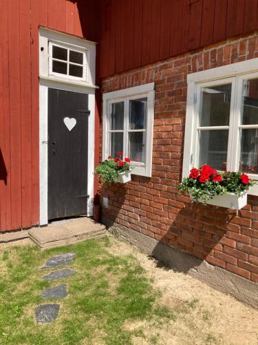 a red house with a black door and two windows at Gård Mörbacka Bed & Breakfast in Mörbacka