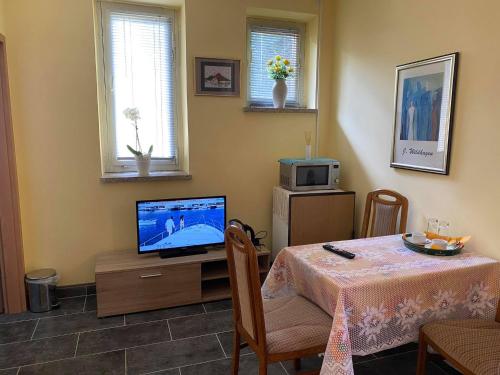 a living room with a table and a television at Pension Goldener Drache in Hohekreuz