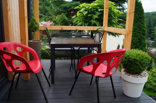 um pátio com cadeiras vermelhas e uma mesa num alpendre em Mały domek w Dolinie Prądnika em Sułoszowa