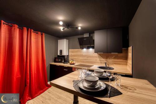 - une cuisine avec des rideaux rouges et une table avec de la vaisselle dans l'établissement La chambre noire au coeur de Metz (unenuitametz), à Metz
