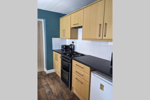 a kitchen with wooden cabinets and black counter tops at Duck & Heron Cottage in Morpeth
