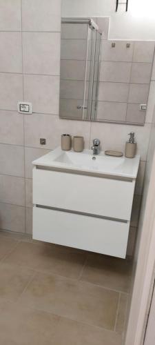 a white bathroom with a sink and a mirror at Casa da Gino in Calasetta