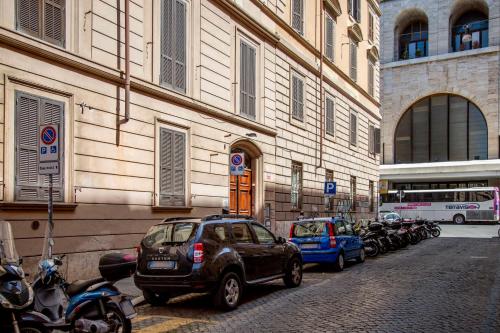 a street with cars and motorcycles parked next to a building at Rome Lucia Apartment in Rome