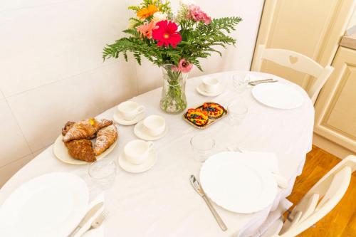 a white table with a vase of flowers and pastries at Rome Lucia Apartment in Rome