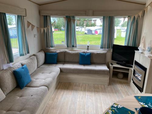 a living room with a couch and a television at 5 mins walk to beach. 3 bedroom caravan. Sleeps 8 in Clacton-on-Sea