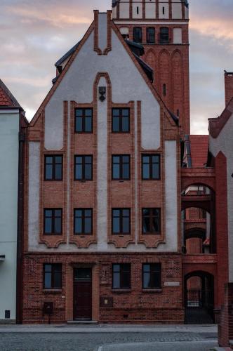 an old brick building with a clock tower at Apartament przy Ścieżce Kościelnej in Elblag