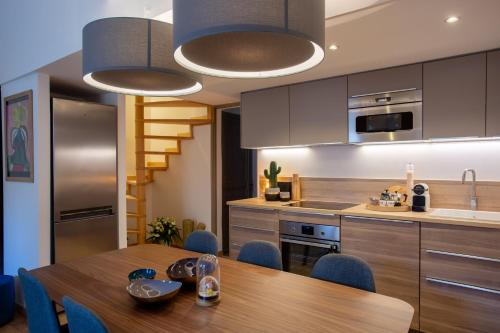 une cuisine avec une table en bois et des chaises bleues dans l'établissement Duplex Flamingo, l'Hauture, Arles, à Arles