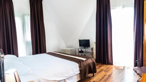 a bedroom with a white bed and a television at Pensiunea LIN COTA 1000 in Sinaia