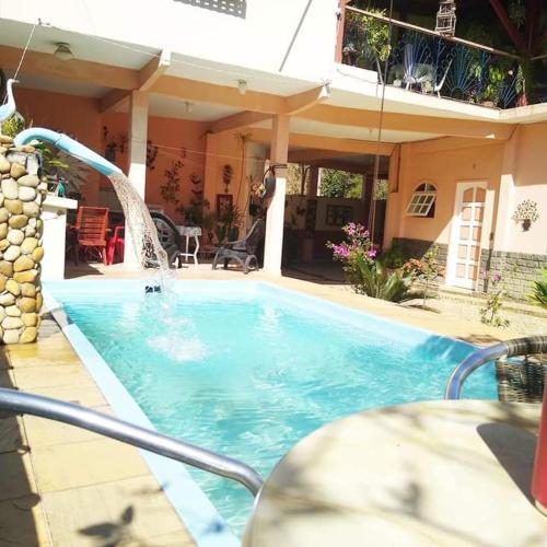 a swimming pool with a fountain in front of a house at Pousada Oca Porã in Conservatória