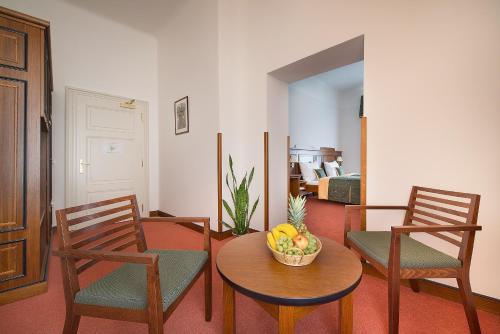 a living room with two chairs and a table with a bowl of fruit at U Medvidku-Brewery Hotel in Prague