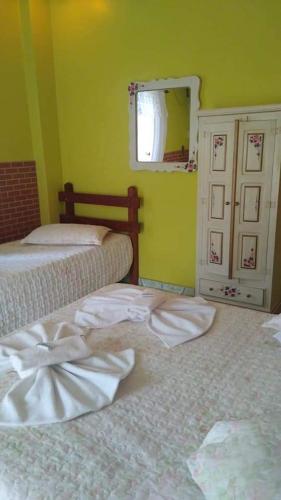 a bedroom with two beds and a window and a mirror at Pousada Oca Porã in Conservatória