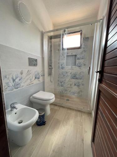 a bathroom with a shower and a toilet and a sink at Villetta Azzurra Kal'è Moru in Geremèas