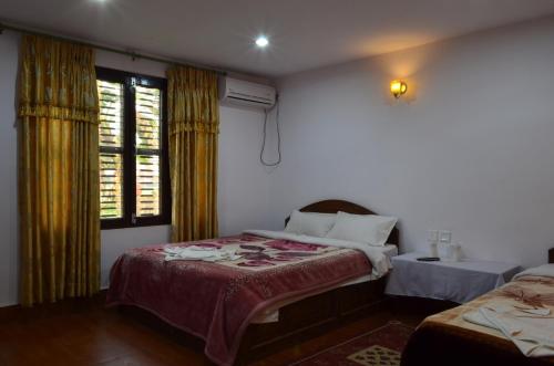 a bedroom with two beds and two windows at Hotel Hermitage in Sauraha