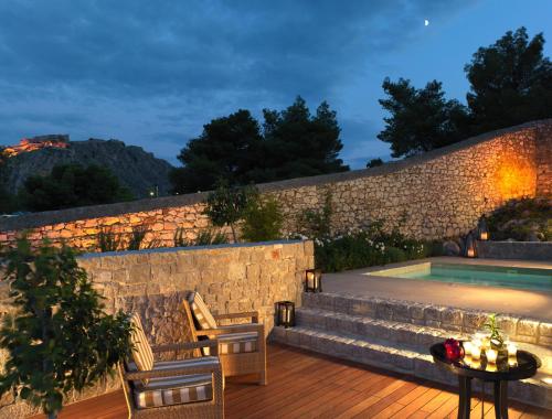 a patio with a table and chairs next to a pool at Nafplia Palace Hotel & Villas in Nafplio