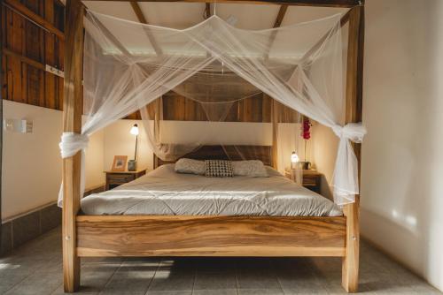 a wooden bed with a canopy in a bedroom at Calalas Lodge in Nindirí