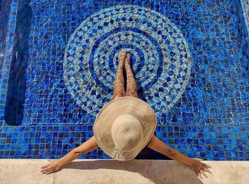 a woman in a straw hat laying on her back in a swimming pool at Cabo Vista Hotel Adults Only in Cabo San Lucas