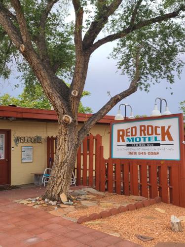 a building with a red rock motel sign next to a tree at Red Rock Motel and Dam Motel in Page