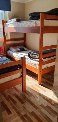 two bunk beds in a room with a wooden floor at Departamento Laguna Bahía 808 Velero in Algarrobo