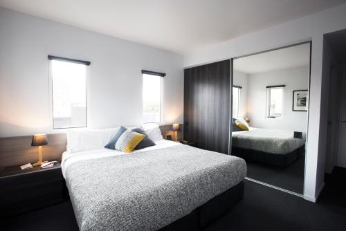 メルボルンにあるTyrian Serviced Apartments Fitzroyのベッド2台と鏡が備わるホテルルームです。