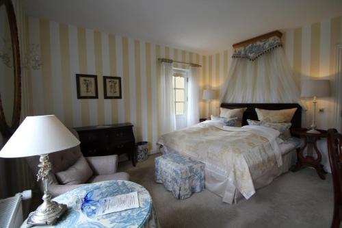 a bedroom with a large bed and a chair at Vraa Slotshotel in Tylstrup