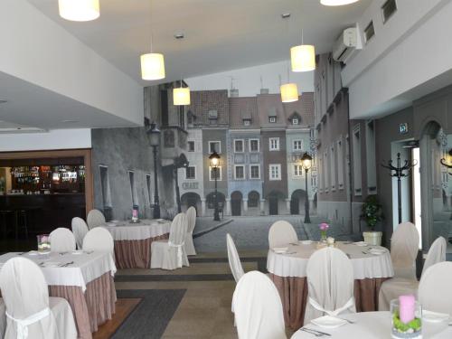 a restaurant with white tables and white chairs and buildings at Hotel Camping Malta in Poznań