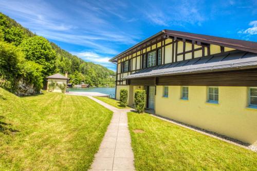 a house with a pathway next to a body of water at Seehotel Billroth in Sankt Gilgen