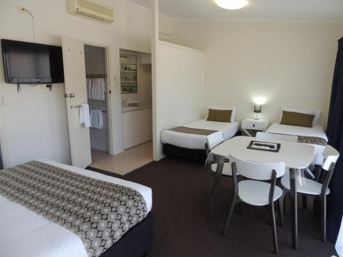 ein Hotelzimmer mit 2 Betten, einem Tisch und Stühlen in der Unterkunft Comfort Inn Premier in Coffs Harbour