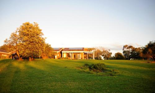 a large house on a green field with a tree at Banksia Park Estate in Phillip Island