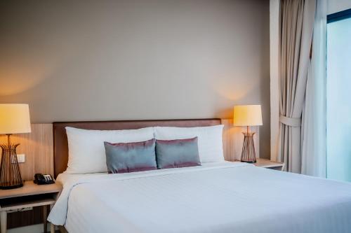 a bedroom with a large white bed with two lamps at The Pago Design Hotel Phuket-SHA Plus in Phuket Town