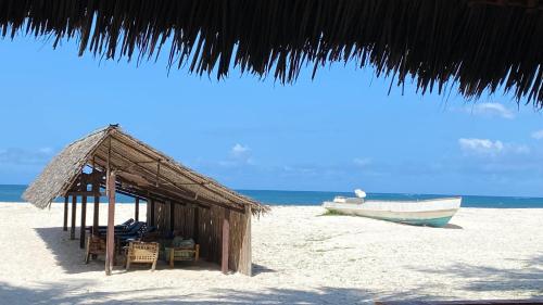 a small shack on the beach with a boat at Pinewood Beach Resort and Spa in Diani Beach
