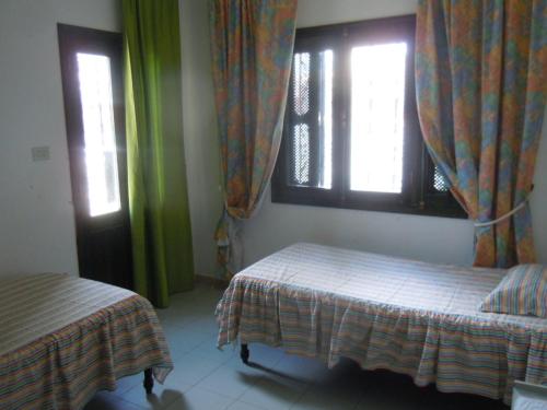 1 Schlafzimmer mit 2 Betten und 2 Fenstern in der Unterkunft House with Wala Garden in Mahdia