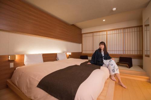 a woman sitting on a bed in a hotel room at Choyo Tei in Kamikawa