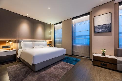 a bedroom with a white bed and a large window at Novotel Tianjin Drum Tower in Tianjin