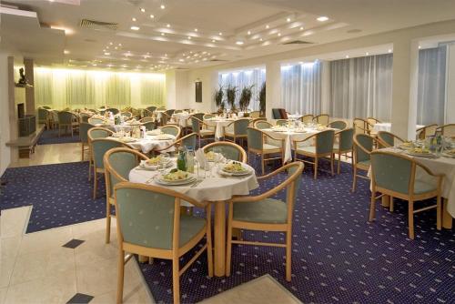 uma sala de jantar com mesas e cadeiras num quarto em Finlandia Hotel em Pamporovo